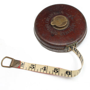 Vintage tape measure with leather case on a white background